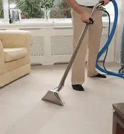 Professional carpet cleaner using a hot-water extraction wand and hose machine in a living room in New Haven, CT.