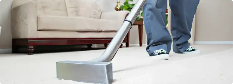 Carpet cleaning technician using a hot-water extraction wand on a light-colored carpet in a living room, New Haven, CT.