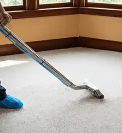 Steam carpet cleaning technician using a hot-water extraction wand on a residential carpet, wearing blue protective shoe covers New Haven, CT.
