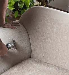 Professional upholstery cleaner deep-cleaning a fabric sofa with a handheld extraction tool and hose New Haven, CT.